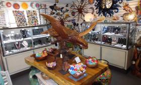 A wooden carving of a sea turtle with glass jewelry displays behind