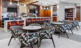 The bar and lounge area at Hyatt Place on Vilano, has round tables with colorful mid-century style chairs