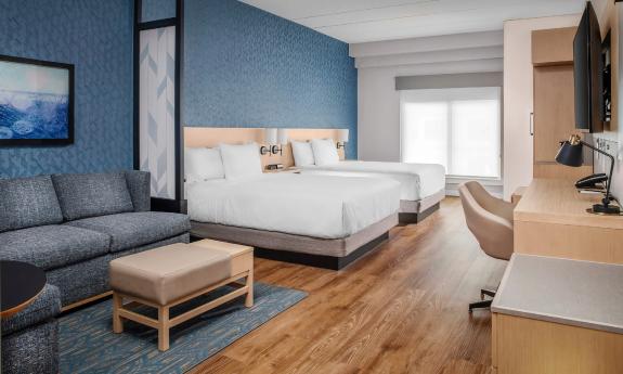 One of the guest rooms at the Hyatt Place Hotel in Vilano Beach, has a teal green accent wall, sofa and desk, and two queen beds