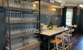 A shelf of glassware and tables arranged inside the French bistro