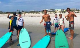Day campers at Stoked to Surf Surf Camp on the beach, with aqua boards