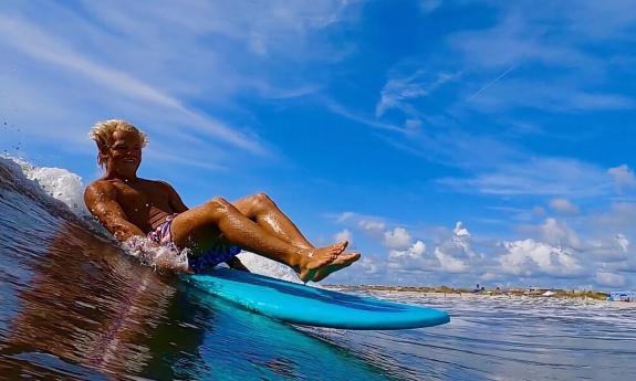 One surfer riding a wave aboard an aqua-blue surf board while sitting