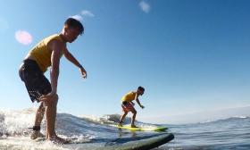 Two boys balance on their surf boards while riding a wave in St. Augsutine