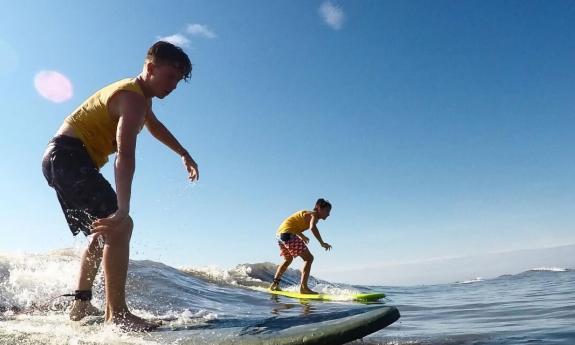 Two boys balance on their surf boards while riding a wave in St. Augsutine