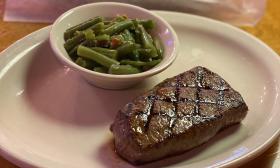 A plate of steak and a side of green beans