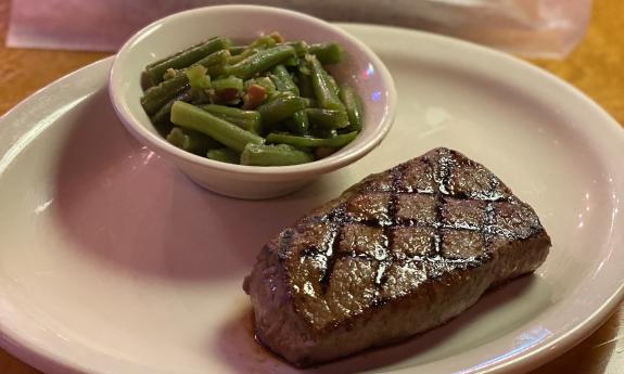 A plate of steak and a side of green beans