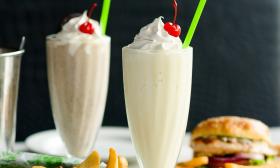Glasses of milkshakes topped with whipped cream and cherries