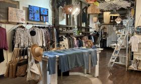 An assortment of trendy clothes for view on racks and tables