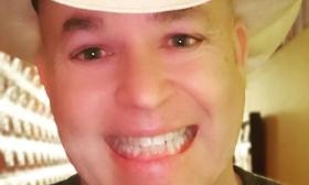 Closeup headshot of $5 Jack, smiling, in a white cowboy hat