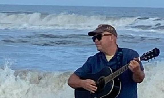 Musician $5 Jack with his guitar, singing at the ocean side