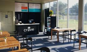 The sun-lit dining area of Crave 312, with the service counter and menu in the background.