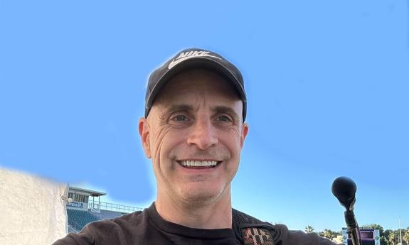 Selfie of Kevin Mark, outside under blue sky, in ball cap