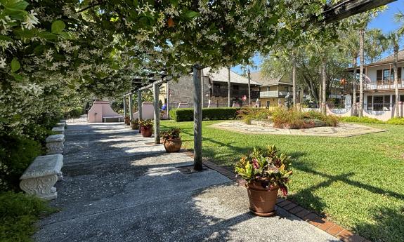 A covered pathway with benches and potted plants lining the sides