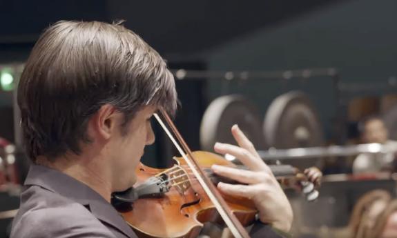 Nigel Armstrong performing on the violin in front of a orchestra