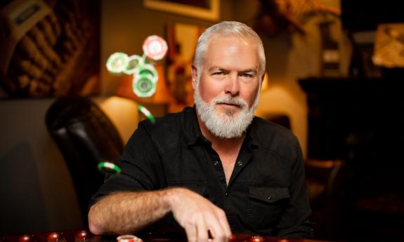Rivers Rutherford in a darkened room, wearing a black shirt