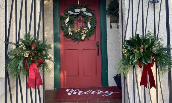 A red door, with iron gates at the side, decorated for the winter holidays