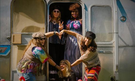 Female band the Vintage Vixens making heart symbol outside Airstream trailer