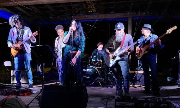 A 6-piece blues band on an outdoor stage at night