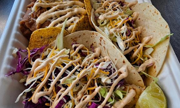A two taco meal with a side of refried beans