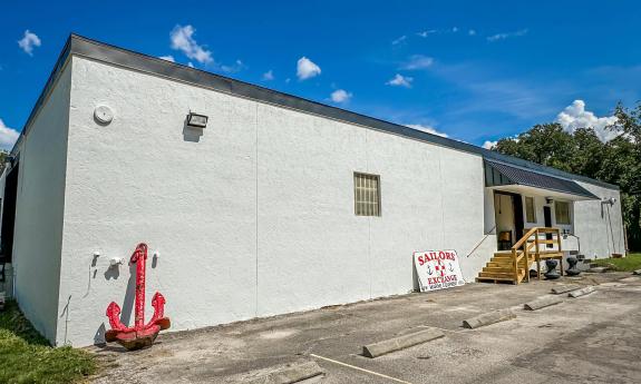 The exterior of the new location for Sailor's Exchange, on a clear day, showing their red anchor