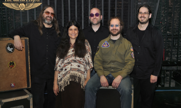 Bandmates from The Garcia Project smile and pose in front of a black backdrop. 