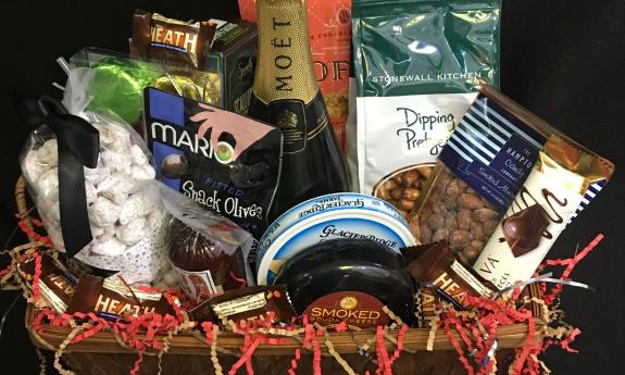 A gift basket with chocolates, savory treats, and a bottle of sparkling wine