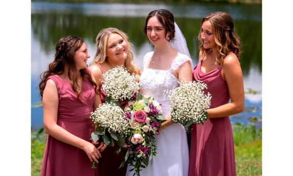 A bride and her three attendants, dressed in coral 