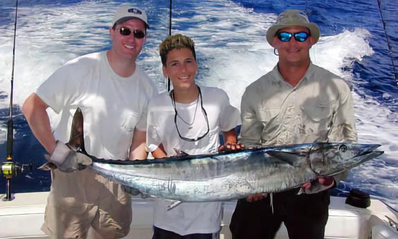 Three men carry a wahoo fish