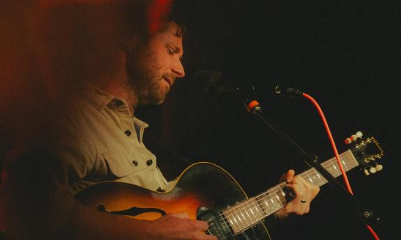 Musician Dan Mangan on stage with a guitar