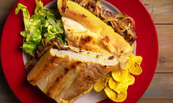 A plated pan con bistec (steak sandwich) with plantain chips