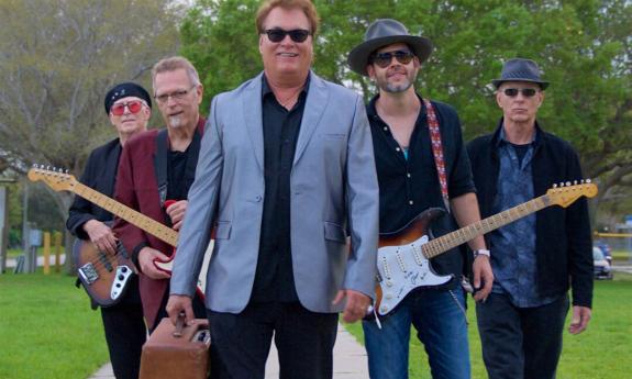 Bandmates from the Backtrack Blues Band smile and pose with their guitars.