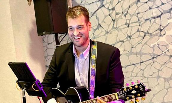 Percussinist Jeremy Price playing guitar at a show.