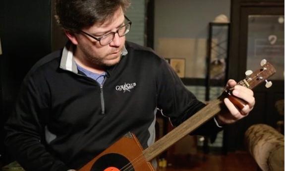 Luthier Kevin Edwards, playing one of his cigar box guitars