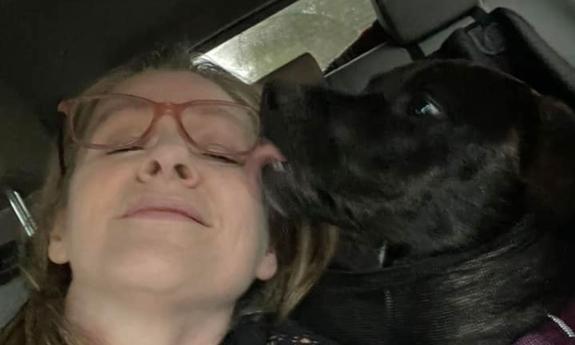 Musician Kim Blackburn's black lab dog licking her glasses off.
