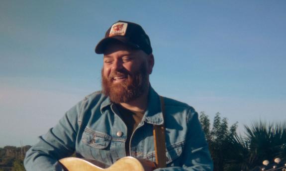 Musician Kirk Whalen, with his guitar, outside