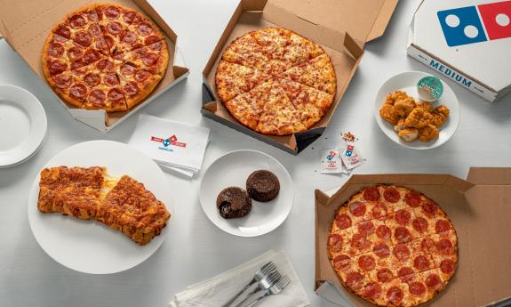 Pizza, side snacks, and dessert presented