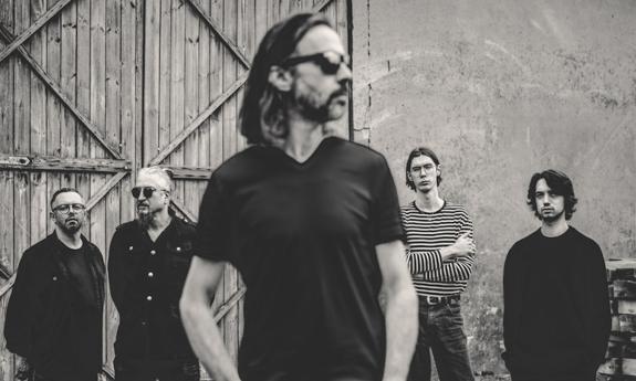 Members of the band Atmosphere pose in front of a barn.