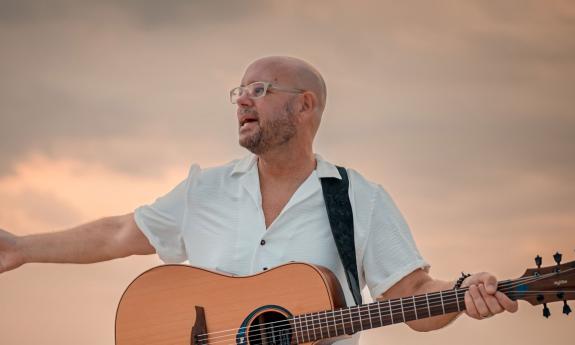 Spiritual musician Bob Sima with guitar, and outstretched hands