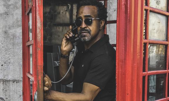 Tim Meadows stands in a phone booth and poses for fans.