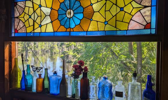 Stetson Kennedy's stained glass window with colorful bottles and a lake view