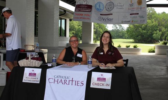 Two women sitting behind the check-in table for a charity golf tournament