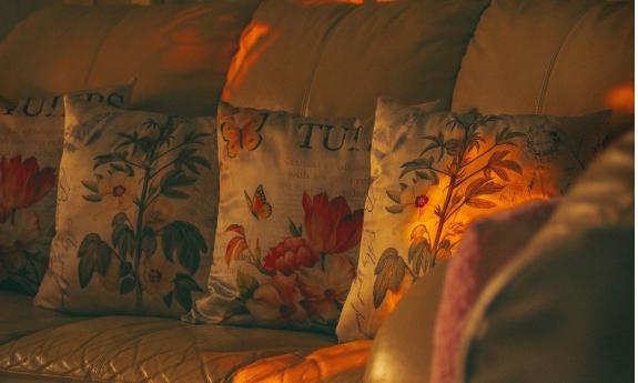 A living room sofa, covered with pillows, and lit by the sun