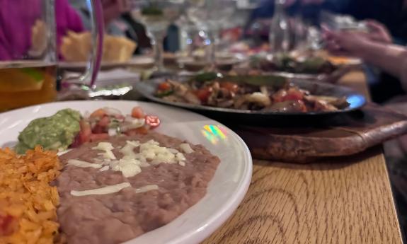 A table laden with Mexican food, being shared by a group of friends