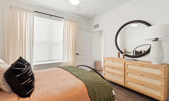 The bedroom with a large window has room for a double dresser