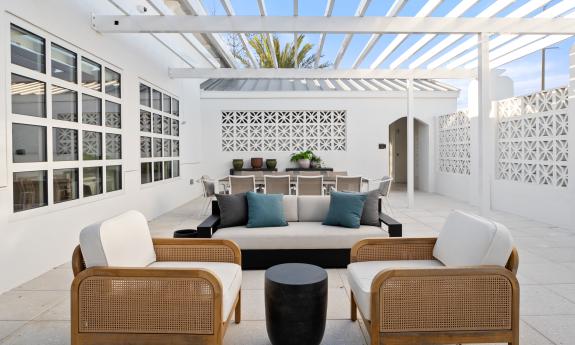 This outdoor lounge is under a pergola and offers multiple seating areas