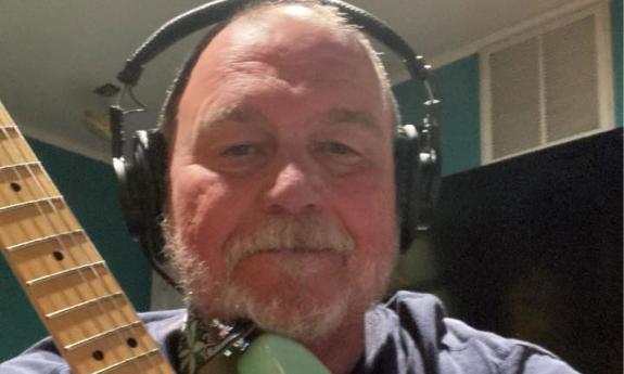 Jim Bickerstaff with guitar, in headset