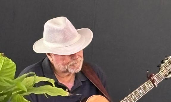 Jim Bickerstaff playing guitar, with face hidden by brim hat