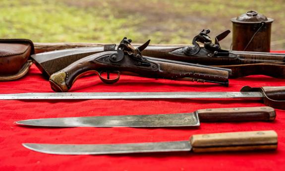 Old knives and firearms displayed on a table during the Battle of Bloody Mose