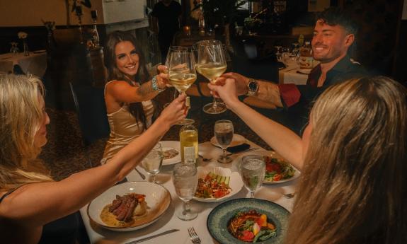 Four friends having a toast before dinner in a restaurant