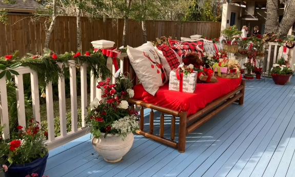 A back deck with an outdoor sofa decorated with greenery and pillows for the holidays